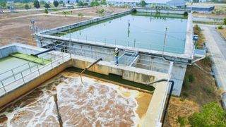 An aerial view showing large, rectangular containers of water with an engineer standing over the edge
