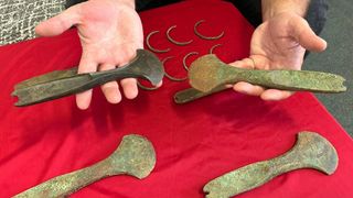 A person holds Bronze Age artifacts
